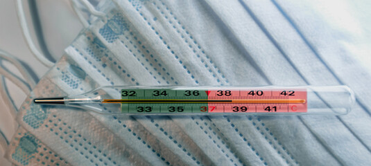 Banner with a medical mercury thermometer close-up. Thermometer shows a high body temperature....