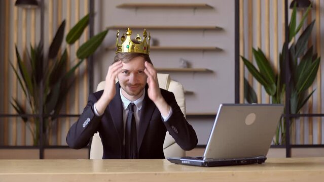 Portrait of young successful businessman investor wearing king crown with envy smile scheming and conspiring, thinking devious tricks and cheats. Leadership concept.