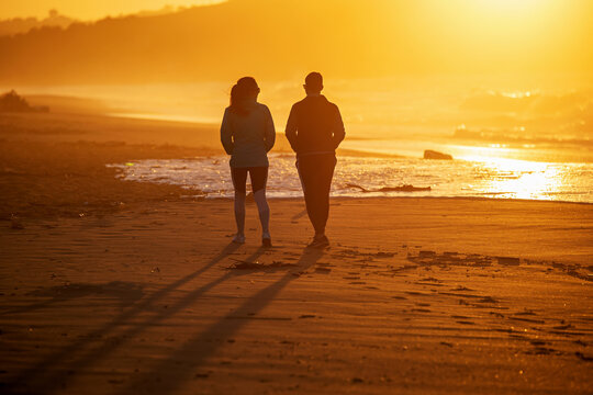 couple strolling along the beach at sunset