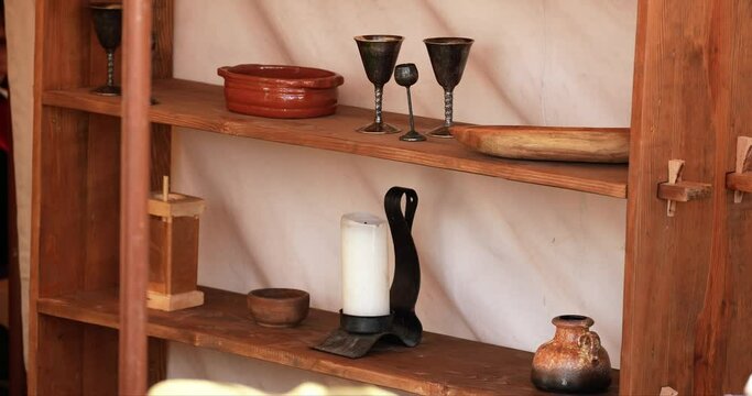an interior of candlestick and cupware and various medieval items placed on a shelf