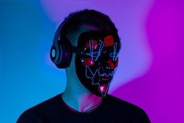 Relaxed Man with Mask Listening Music In Wireless Earphones In Neon Light