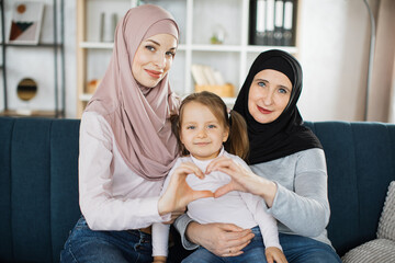 Portrait of smiling three generations of muslim women have fun posing for self-portrait picture...