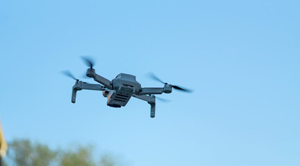 Consumer drone with camera hovering against sky with copy space