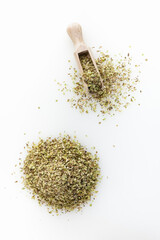 Heap of dried oregano. Wooden scoop. Isolated on white background. Top view.