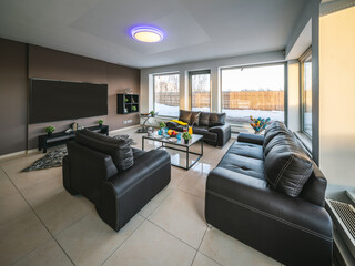 Modern interior of spacious living room in luxury private house. Black leather furniture