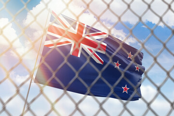 A steel mesh against the background of a blue sky and a flagpole with the flag of new zealand