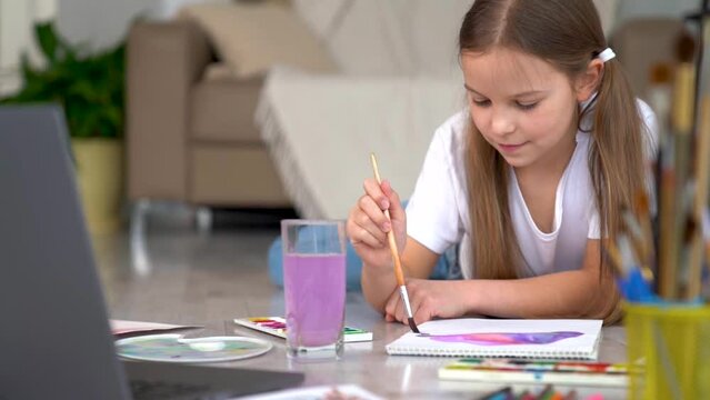 Remote school art lessons. Child smiles studies and gets knowledge remotely. Little girl study online at home does homework. Distance learning education. Quarantine and Social distancing concept.