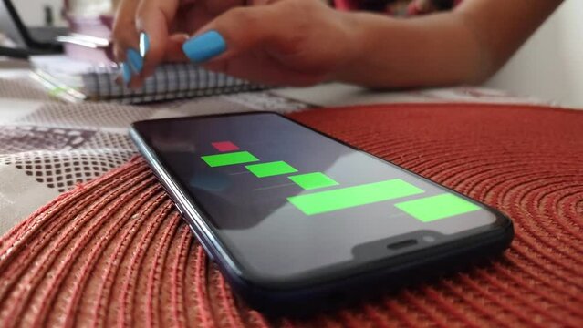 Pessoa operando no mercado financeiro pelo smartfone 