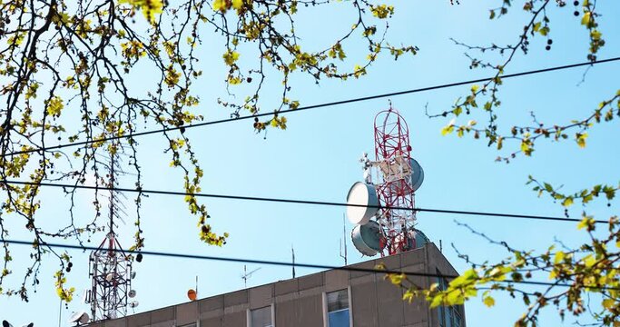 large antennas and repeaters for mobile telephony on the roof of the city building through the canopy of trees