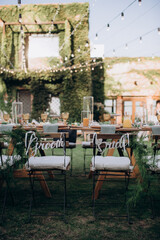 chairs of the newlyweds at the festive table with the inscription