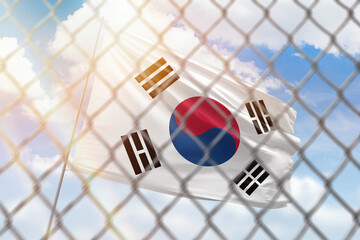 A steel mesh against the background of a blue sky and a flagpole with the flag of south korea