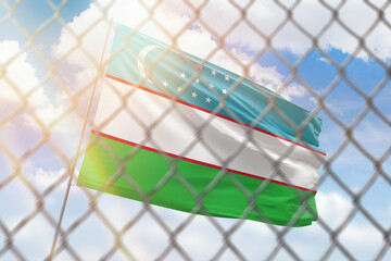 A steel mesh against the background of a blue sky and a flagpole with the flag of uzbekistan