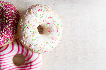 Two colorful donuts on wooden white background, close up