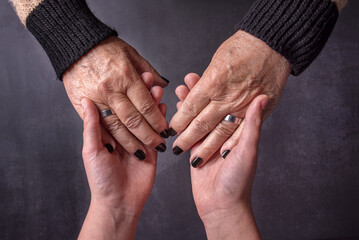 Hands of an old woman and her grandson holding hands.