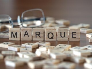 marque word or concept represented by wooden letter tiles on a wooden table with glasses and a book