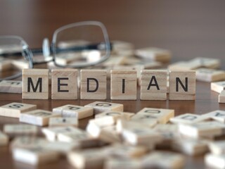 median word or concept represented by wooden letter tiles on a wooden table with glasses and a book