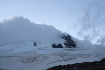 Alpine landscape. View of Tronador hill mountain peak, snow and glacier Castaño Overo ice field, at sunrise in a cloudy morning. 