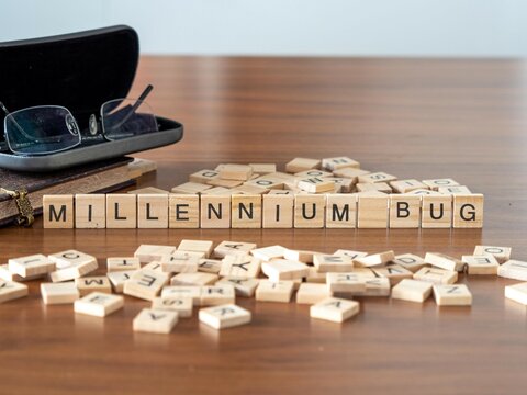 Millennium Bug Word Or Concept Represented By Wooden Letter Tiles On A Wooden Table With Glasses And A Book