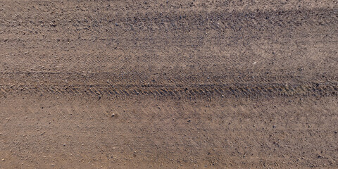 panorama of surface from above of gravel road with car tire tracks