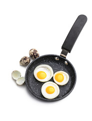 Fried quail eggs in onion ring in frying pan isolated on white