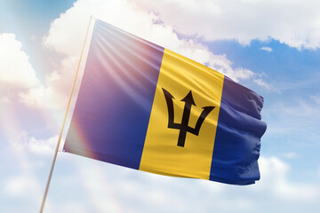 Sunny blue sky and a flagpole with the flag of barbados