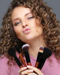 Applying Make-up. Grimacing and smiling girl with makeup brushes
