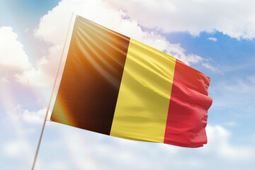 Sunny blue sky and a flagpole with the flag of belgium