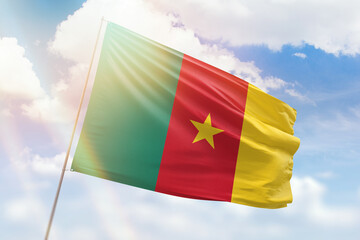 Sunny blue sky and a flagpole with the flag of cameroon