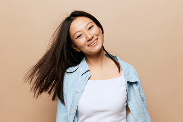 Dancing cheerful tanned adorable young Asian lady spinning waving her hair posing isolated on beige pastel background. People and Emotions. Happiness concept. Copy Space Offer Banner.