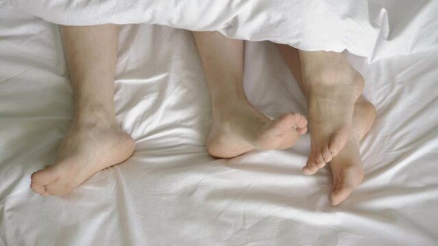 Couple in bed. Male and female legs top view on a white bed. 4k