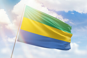Sunny blue sky and a flagpole with the flag of gabon
