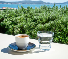 Turkish coffee and a glass of water on a white table on the terrace in a cafe