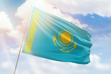 Sunny blue sky and a flagpole with the flag of kazakhstan