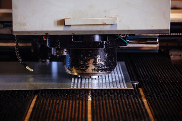 CNC punching and nibbling machine and perforated steel sheet, close up