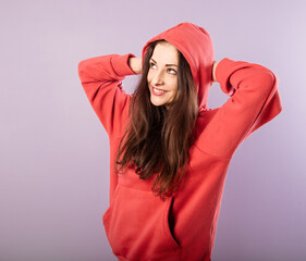 Fun enjoying toothy smiling woman thinking and looking up  in fashion red hoodie on purple bright background with empty copy space.