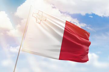 Sunny blue sky and a flagpole with the flag of malta