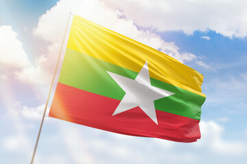 Sunny blue sky and a flagpole with the flag of myanmar