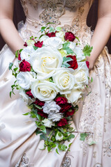 Bouquet of white roses and red roses held by the bride