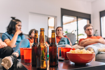 Close-up of a table full of drinks and snacks for a party. Friends watching football in the living room