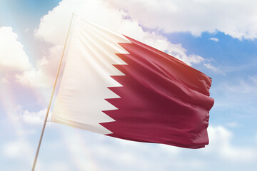 Sunny blue sky and a flagpole with the flag of qatar