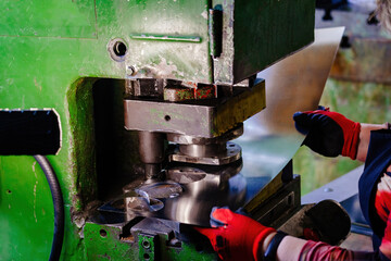 Worker operating metal press stamping machine, close up