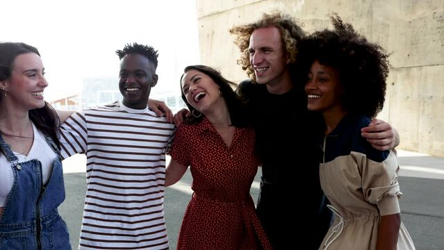 Happy multiracial people standing together outdoors - Friendship concept with group of young friends from diverse cultures and races having fun while smiling. High quality 4k footage