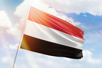 Sunny blue sky and a flagpole with the flag of yemen