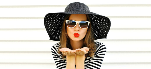 Portrait of beautiful young woman blowing her lips with red lipstick sending sweet air kiss wearing...