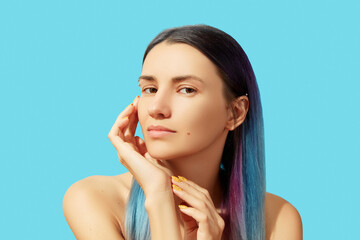 Face of young beautiful woman with blue hair on bright background