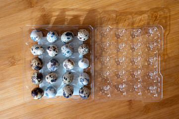 Quail eggs in plastic transparent packaging on a wooden table. High quality photo