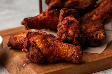 Fried Chicken Wings Covered in True Hot BBQ Sauce served with red hot chilli sauce on a Cutting Board on marble background.