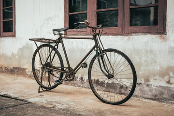 Old bike against the wall at home, old bicycle in vintage style.