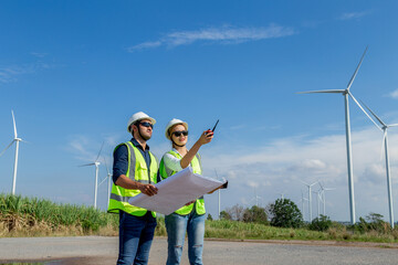 Asian man and woman engineers working on site in wind turbine on the background. Young people...