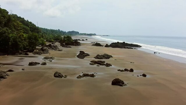 Drone View Flying Over Empty Beach During Low Tide On Cloudy Day.